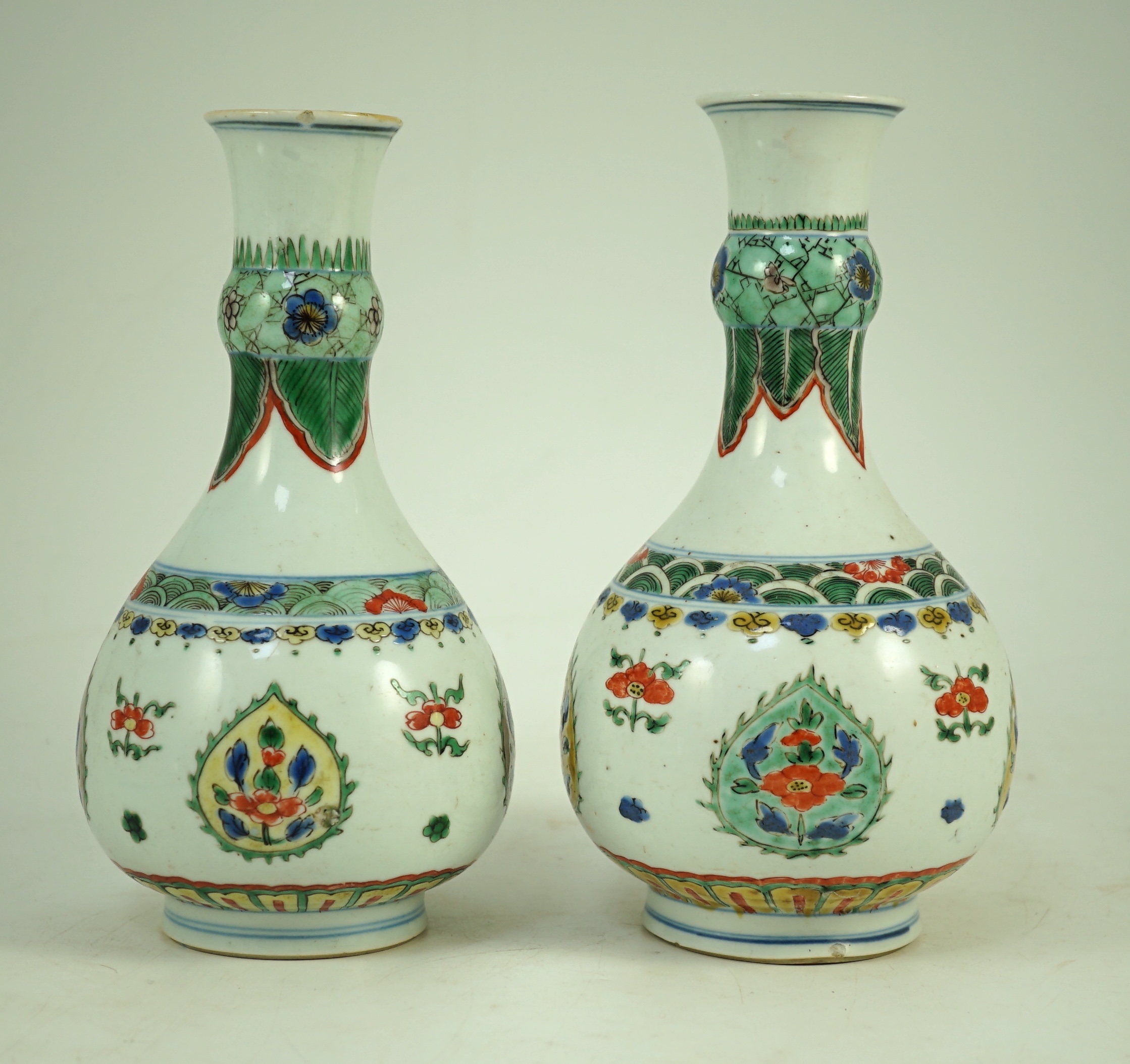 A near pair of Chinese famille verte garlic-neck vases, Kangxi period, 20cm and 20.5cm high, One vase restored